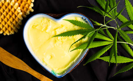 Butter with cannabis plant in a heart shape bowl top viewの写真素材