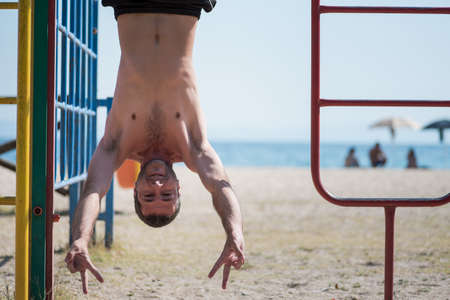 Man hanging upside down at the beach in Greece