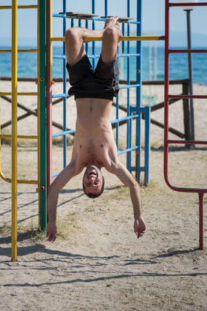 Man hanging upside down at the beach in Greece