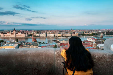 Woman enjoying Hungarian Parliament view in Budapest buy the Danube river at sunsetの写真素材