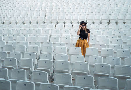 Fashionable girl in an empty theater with white seatsの写真素材