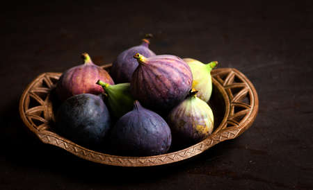 Fresh figs in a bowl on a wooden tableの写真素材