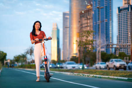 Woman using electric scooter for transportation in a modern city environmentの写真素材