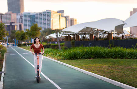 Woman riding electric scooter for transportation in a modern city environmentの写真素材