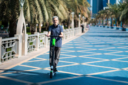Senior using electric scooter for transportation in a modern city environmentの写真素材
