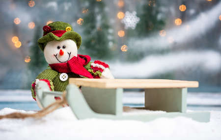 Toy snowman with sledges and festive illuminated Christmas holiday background