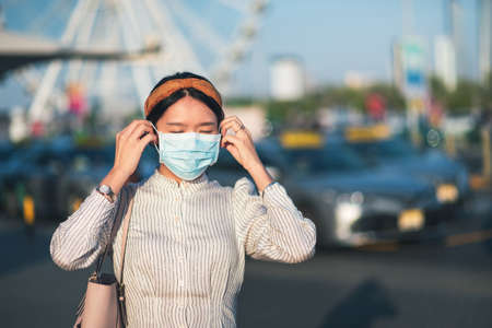 Asian girl wearing face mask at a parking lot outdoorsの写真素材