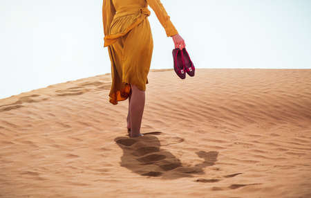 Woman walking in a desert on a sunny day rear low angle view