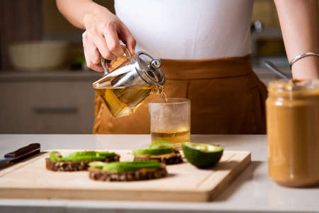 Woman making morning tea to have with breakfast at homeの写真素材