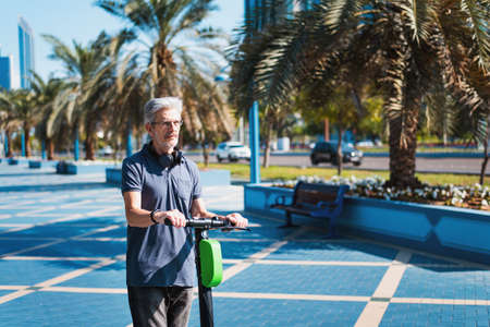 Senior using electric scooter for transportation in a modern city environment. Healthy senior lifestyle outdoorsの写真素材