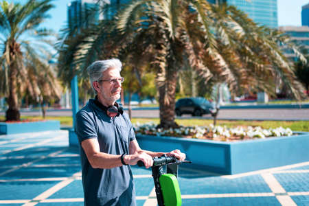 Senior using electric scooter for transportation in a modern city environment. Healthy senior lifestyle outdoorsの写真素材