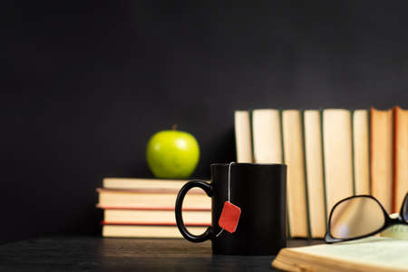 Pile of books with cup of tea for reading on a dark table with copy spaceの写真素材