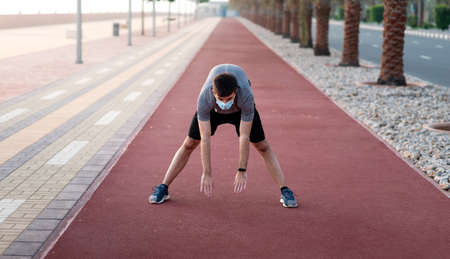 Man exercising while wearing surgical mask to protect from virus spread outdoors