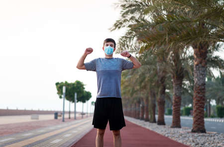 Man exercising while wearing surgical mask to protect from virus spread outdoorsの写真素材
