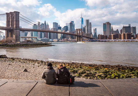 Young couple watching the Brooklyn bridge and lower Manhattan in the winterの写真素材