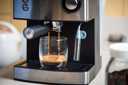 Espresso brewing from a coffee maker in a glass closeupの写真素材