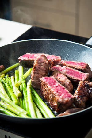 Beef steak frying on the pan with baby asparagus closeupの写真素材
