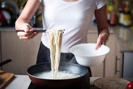 Woman cooking noodles in the kitchen. Home food preparationの写真素材