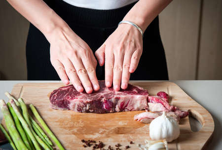 Woman preparing Wagyu Japanese beef steak in the kitchen. Home cooking and food preparationの写真素材
