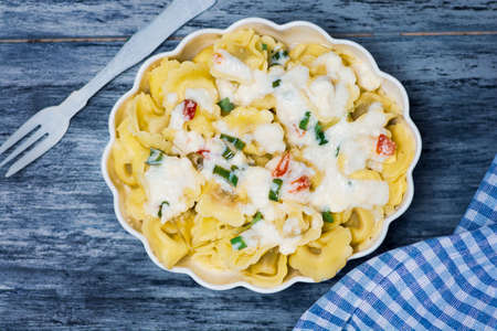 Tortellini Italian stuffed pasta on a plate with cheese and vegetablesの写真素材
