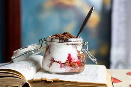 Strawberry parfait dessert in a glass jar on top of books closeupの写真素材