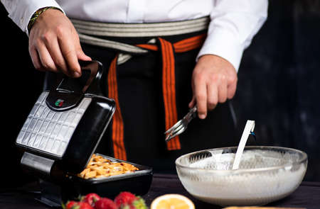 Man making waffles on a waffle machine close upの写真素材