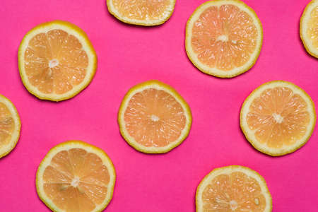 Lemon fruit slices on pink background flat lay top view patternの写真素材