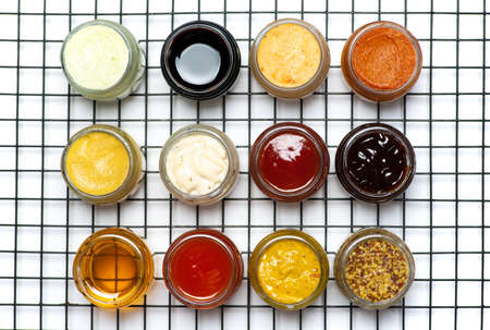Large collection of sauces and spiced spreads in small jars as mayo ketchup mustard soy sauce and many moreの写真素材