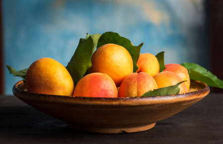 Ripe Apricot fruit isolated on a wooden table in a bowl closeupの写真素材