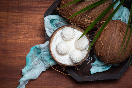 Open and grated coconut fruit on a wooden table with coconut dessert balls top viewの写真素材