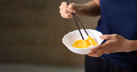 Woman beating eggs with chopsticks closeup, Asian food preparation and cooking abstractの写真素材