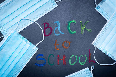 Back to school note with surgical face mask flat lay pattern on the blackboardの写真素材