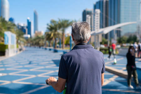 Senior man having a ride on electric scooter for transportation in a modern city environment back viewの写真素材