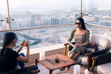 Woman girl friends taking photos in the high view coffee bar at sunset. Female friendship and fun...