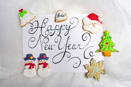 Happy New Year card handwritten with handmade decorated Christmas cookies for festive winter season top view flat layの写真素材