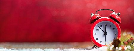 Vintage clock approaching midnight against red Christmas background with large copy space. New Year...