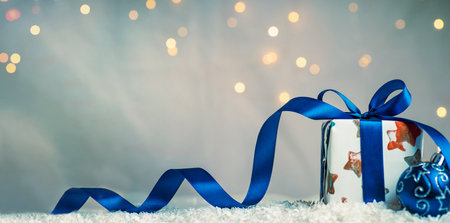 Wrapped Christmas present with festive illuminated background environment and copy space