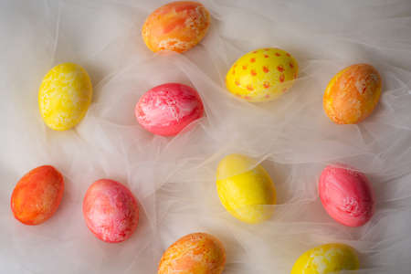 Hand painted pastel colored Easter eggs on white silky fabric closeup