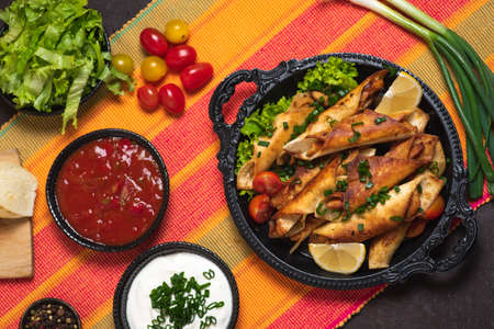 Homemade small tacos with chicken, dipping sauces and food ingredients called taquitosの写真素材