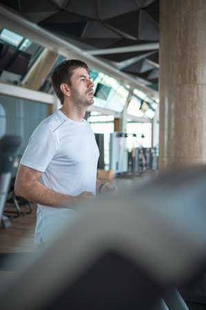 Man jogging on a treadmill during a cardio running warmup exercise in the gym for staying fit and in shape with fitness lifestyleの写真素材
