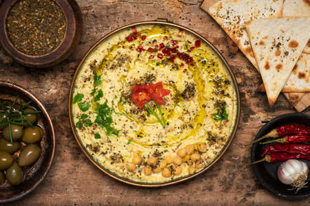 Hummus dipping sauce made of chickpeas, sesame and other ingredients, traditionally used in Mediterranean and Middle Easter cuisines, served in a bowl on a table top viewの写真素材