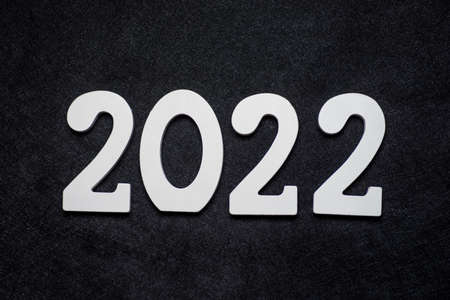 New Year 2022 sign made of wood on festive background with copy space. White painted wood created the inscription Number 2022 on a black background.の写真素材