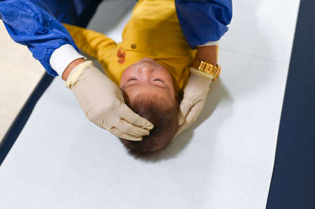 Doctor checking fontanelle of a development of a 5 months old mixed race baby boy at the doctors office for a routine checkup and physical exam to track progress at the hospitalの写真素材