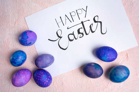 Blue purple Easter eggs with lace look and calligraphic inscription Happy Easter on a pastel background.の写真素材