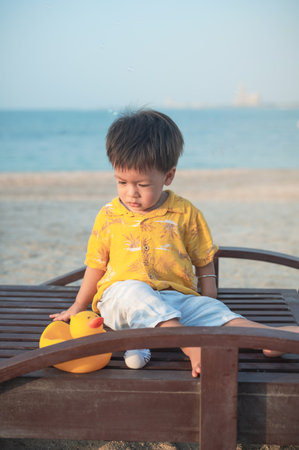 Baby boy on a beach holiday sitting on the sunbed at sunset. One year old male infant on the vacation by the seaside sitting on the sunbedの写真素材