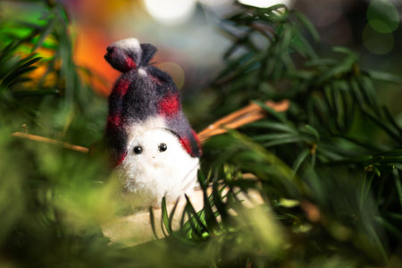 Toy snowman with festive winter holiday decoration and the Christmas tree with shiny fairy lights in...