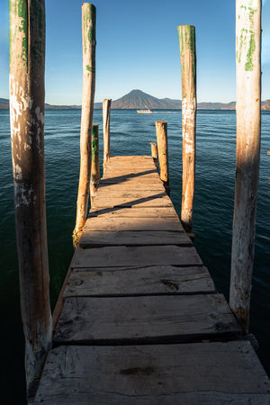 Wooden dock on Lake Atitlan on the beach in Panajachel, Guatemala. With Toliman and San Pedro volcanoes in the background. A beautiful bay of lake with a view of the volcanoes in the highlands of Guatemalaの写真素材