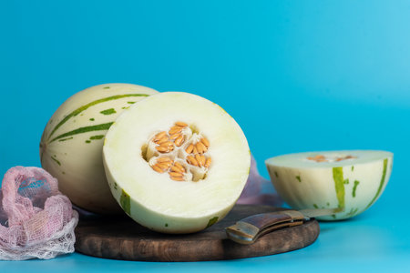 Ivory gaya melon with green dotted stripes and spots on a blue background. Colorful ripe juicy and...