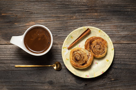 Freshly baked sweet and crispy cinnamon rolls. On a wooden background, with a cup of coffee