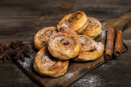 Freshly baked sweet and crispy cinnamon rolls. On a wooden cutting board, with powdered sugarの写真素材
